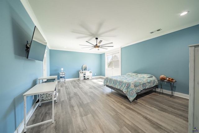 bedroom featuring crown molding, visible vents, a ceiling fan, wood finished floors, and baseboards