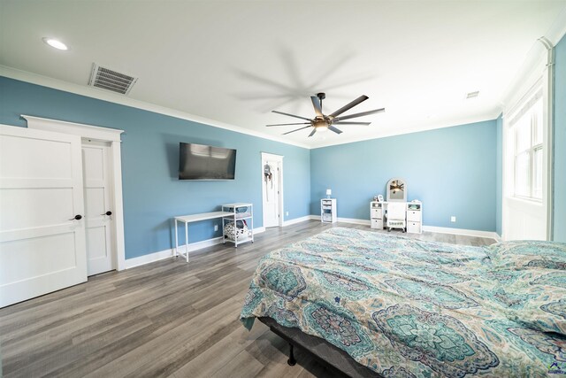 bedroom featuring baseboards, visible vents, crown molding, and wood finished floors