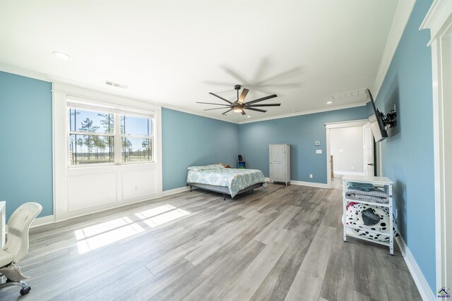 bedroom with baseboards, visible vents, crown molding, and light wood finished floors