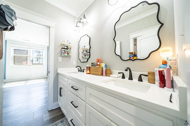 bathroom with double vanity, wood finished floors, a sink, and crown molding