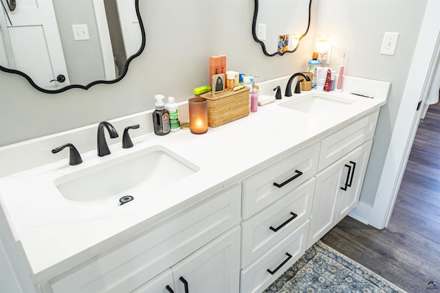 full bath with double vanity, a sink, and wood finished floors