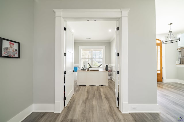 hallway featuring light wood-type flooring, an inviting chandelier, and baseboards
