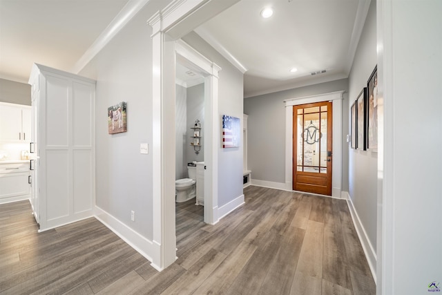 foyer entrance with light wood-style floors, baseboards, visible vents, and ornamental molding