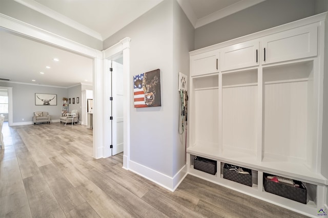 mudroom featuring light wood finished floors, ornamental molding, visible vents, and baseboards