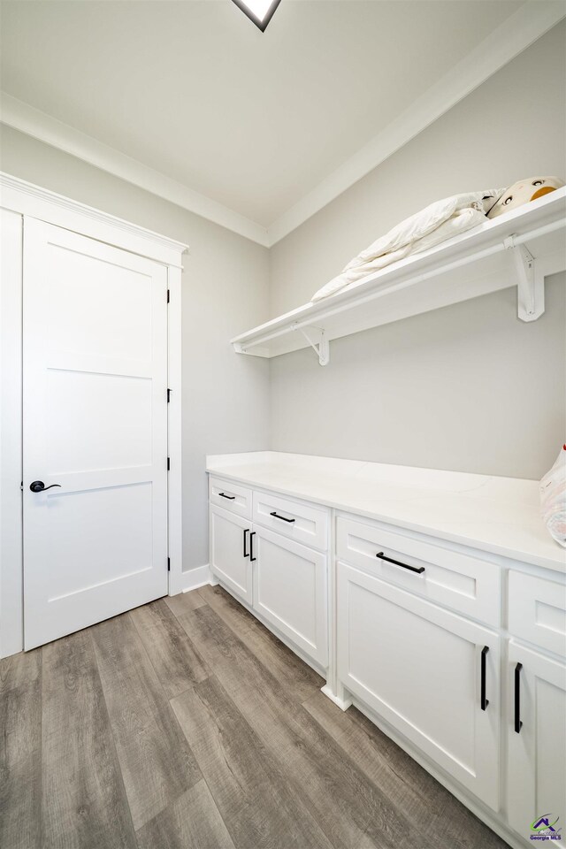 laundry room featuring light wood-type flooring and crown molding