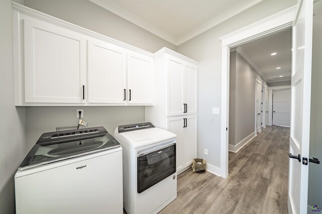 washroom featuring light wood finished floors, cabinet space, ornamental molding, independent washer and dryer, and baseboards