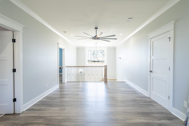unfurnished room featuring baseboards, attic access, ornamental molding, and wood finished floors