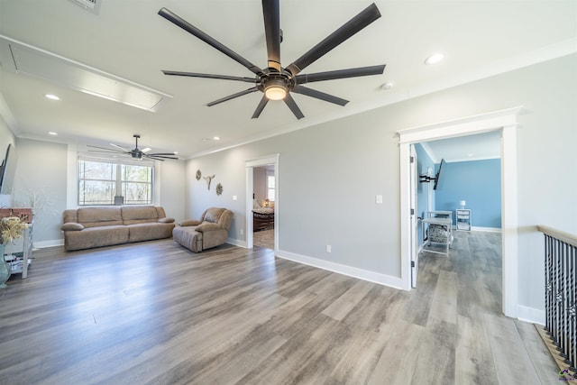 living area with light wood-type flooring, attic access, and crown molding