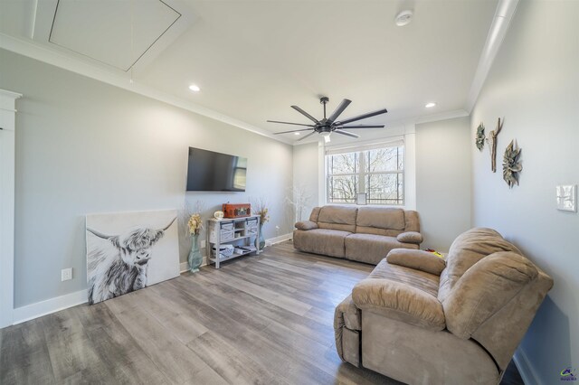 living area featuring baseboards, wood finished floors, attic access, and crown molding