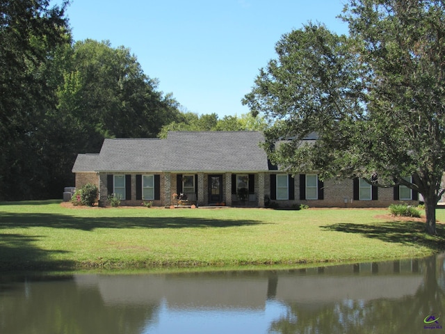 single story home featuring a front yard, a water view, and brick siding