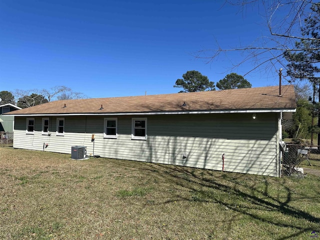 rear view of house with central AC and a lawn