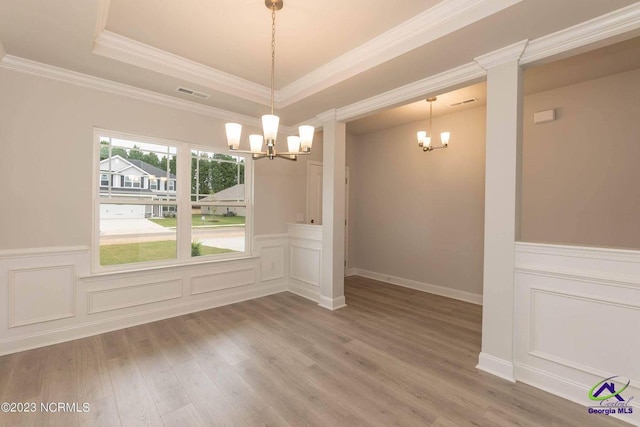 unfurnished dining area with visible vents, a raised ceiling, a notable chandelier, and wood finished floors