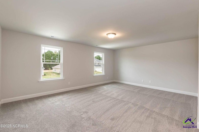 spare room with carpet floors, visible vents, and baseboards