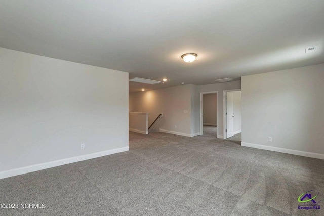 spare room with carpet floors, visible vents, and baseboards