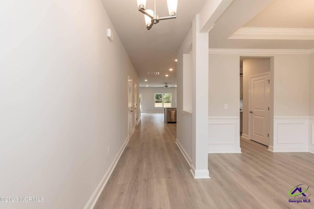 hallway featuring a wainscoted wall, light wood-style flooring, visible vents, and a decorative wall