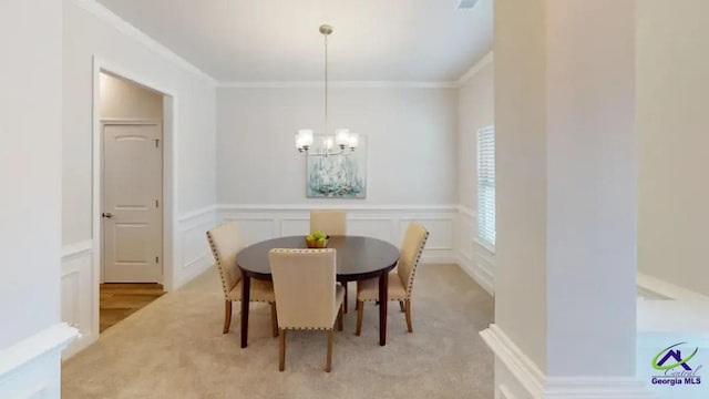 dining area featuring light colored carpet, a wainscoted wall, a decorative wall, ornamental molding, and an inviting chandelier