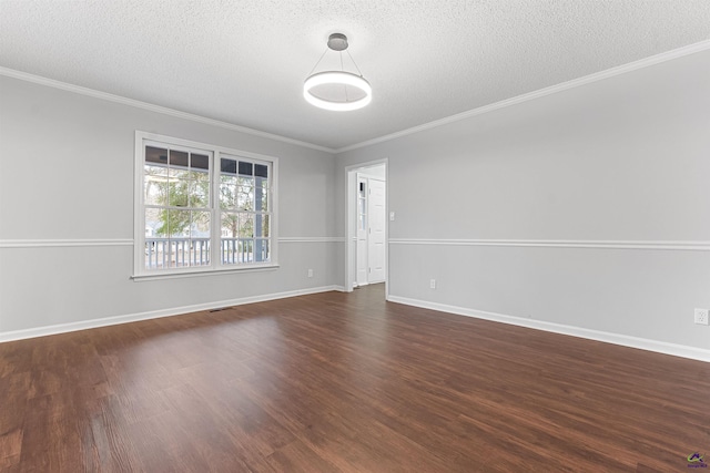empty room featuring a textured ceiling, crown molding, dark wood finished floors, and baseboards