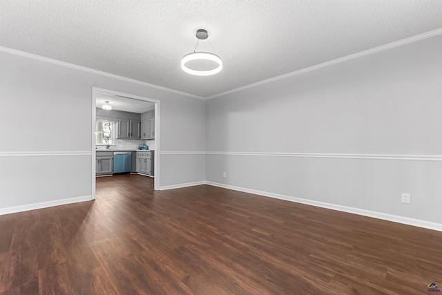 unfurnished living room with ornamental molding, dark wood-style flooring, a textured ceiling, and baseboards
