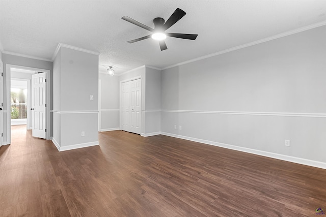 spare room featuring dark wood-style floors, ornamental molding, a textured ceiling, and baseboards