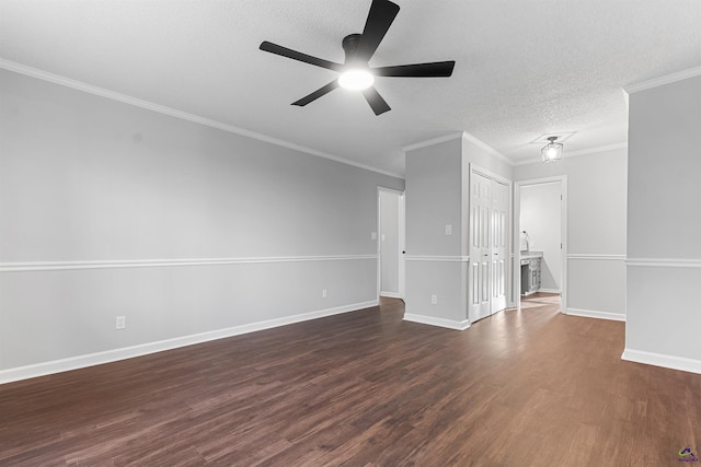 empty room featuring crown molding, dark wood finished floors, ceiling fan, a textured ceiling, and baseboards
