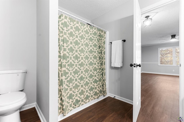 bathroom with toilet, a textured ceiling, baseboards, and wood finished floors