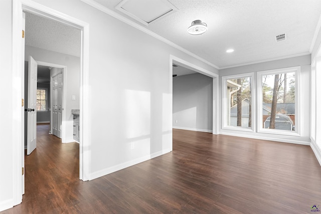 unfurnished room featuring a textured ceiling, visible vents, baseboards, dark wood finished floors, and crown molding