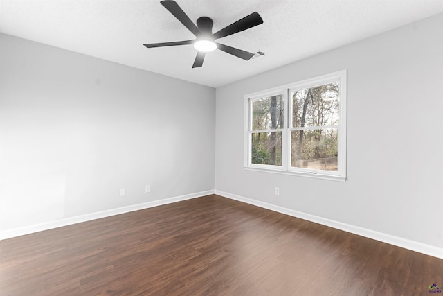 unfurnished room featuring dark wood-style flooring, a textured ceiling, and baseboards