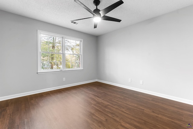 unfurnished room with a textured ceiling, dark wood-style flooring, visible vents, and baseboards