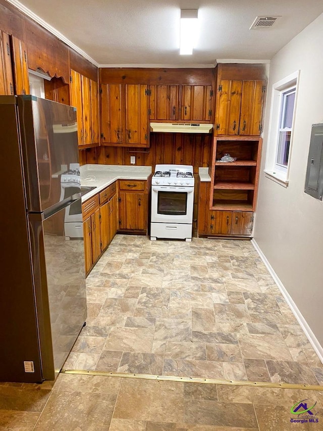 kitchen with electric panel, brown cabinets, freestanding refrigerator, white gas range, and under cabinet range hood