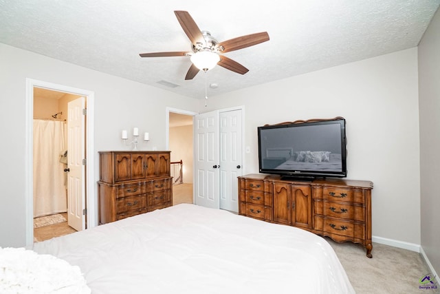 bedroom featuring a textured ceiling, light carpet, visible vents, a closet, and ensuite bath