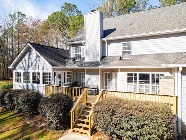 rear view of property with roof with shingles, stairway, a chimney, and a wooden deck