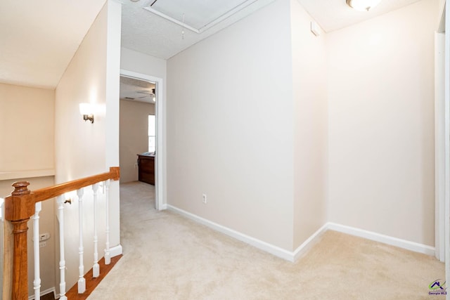 hall featuring attic access, baseboards, carpet floors, and an upstairs landing