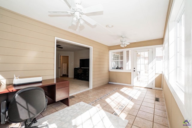 unfurnished office featuring a ceiling fan, visible vents, wood walls, and light tile patterned floors