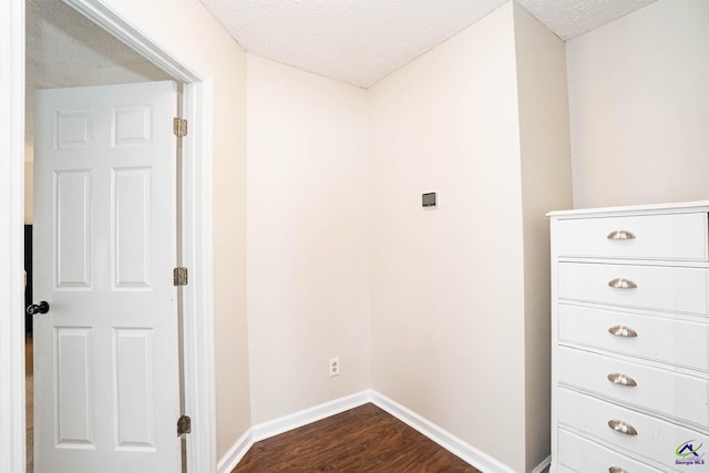 corridor featuring baseboards, dark wood finished floors, and a textured ceiling