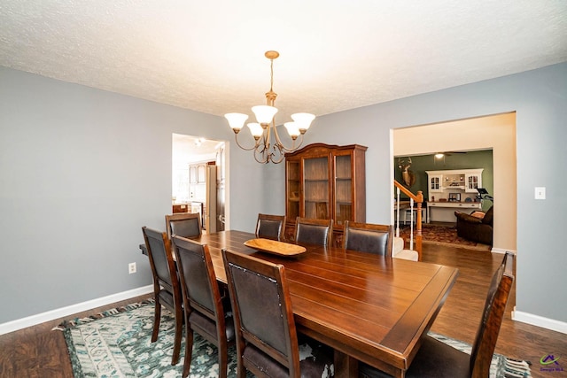 dining area featuring a chandelier, a textured ceiling, wood finished floors, and baseboards