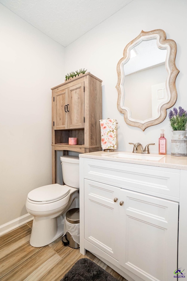 half bath featuring toilet, wood finished floors, and vanity