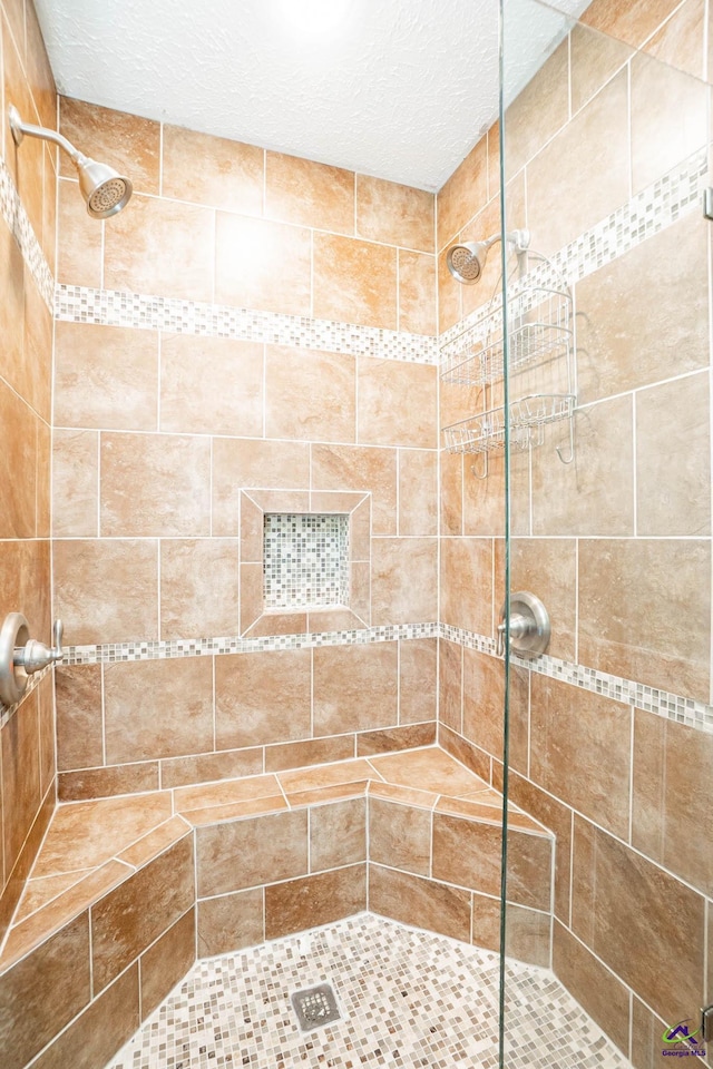 bathroom with a stall shower and a textured ceiling