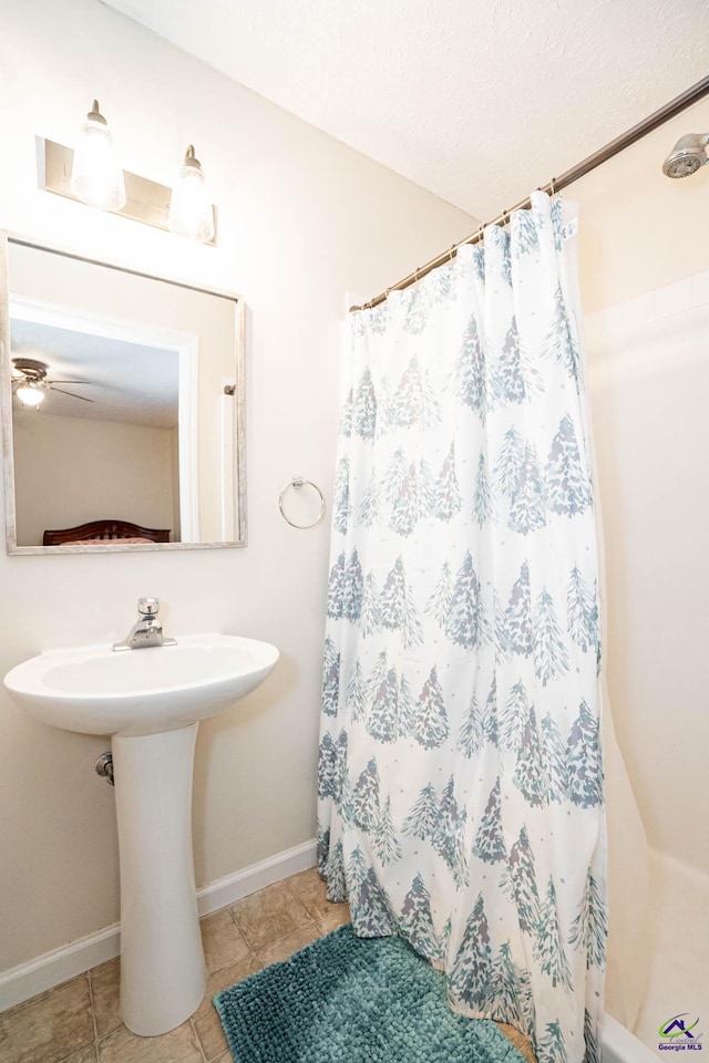 bathroom featuring ceiling fan, a textured ceiling, curtained shower, tile patterned flooring, and baseboards