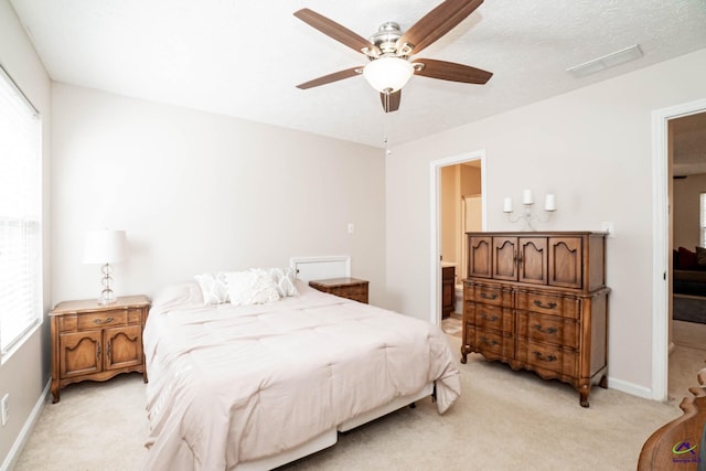 bedroom with light carpet, baseboards, visible vents, ensuite bath, and a textured ceiling