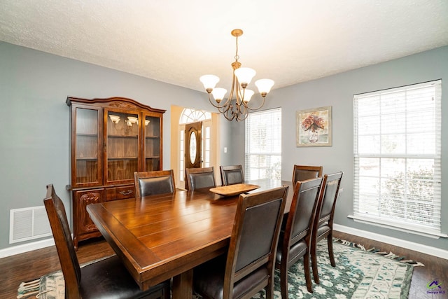 dining space with a chandelier, dark wood-style flooring, visible vents, and plenty of natural light