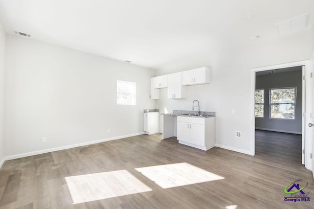 kitchen with white cabinetry, light wood-style flooring, visible vents, and a sink