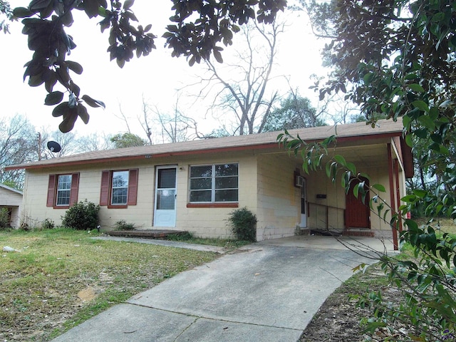 single story home featuring an attached carport, concrete block siding, and a front lawn