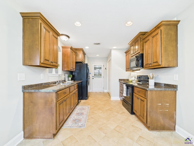 kitchen featuring brown cabinetry, black appliances, baseboards, and a sink