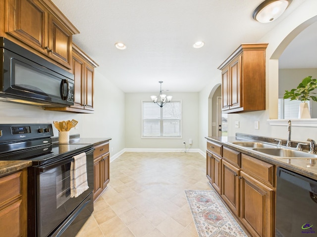 kitchen with baseboards, a chandelier, brown cabinetry, black appliances, and a sink