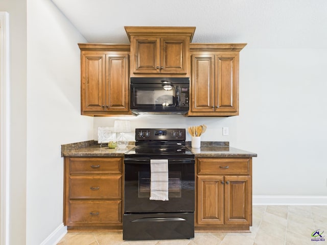 kitchen featuring dark stone countertops, baseboards, black appliances, and brown cabinetry