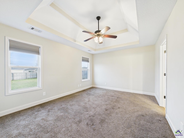 unfurnished room with a ceiling fan, baseboards, visible vents, carpet floors, and a tray ceiling