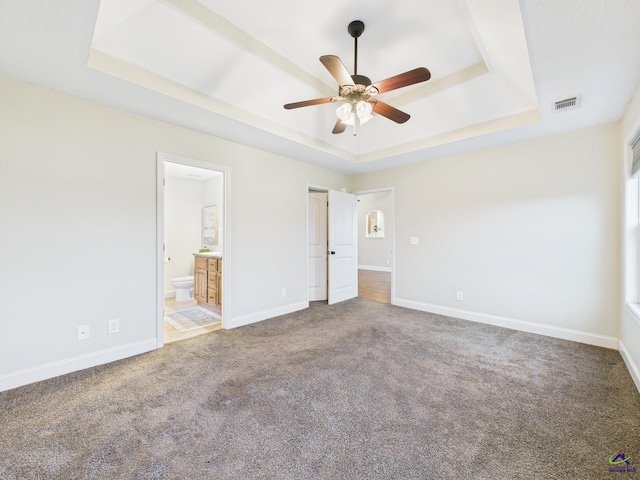 unfurnished bedroom featuring visible vents, baseboards, carpet, and a tray ceiling