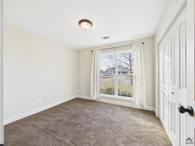 carpeted spare room featuring visible vents and baseboards