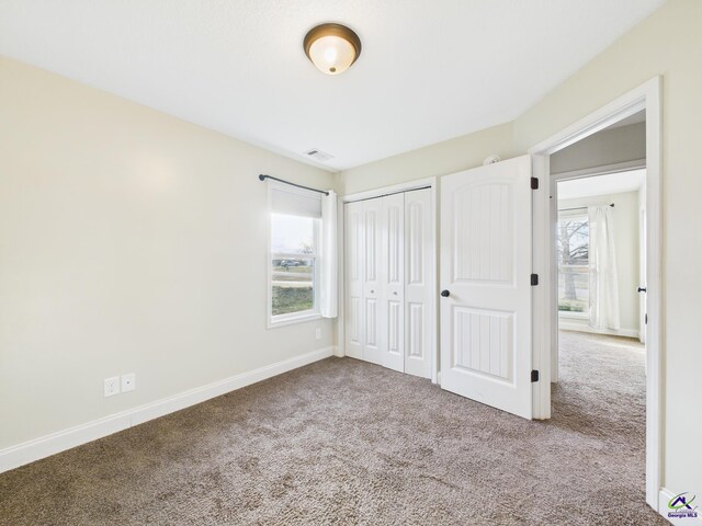 unfurnished bedroom with a closet, visible vents, baseboards, and carpet floors