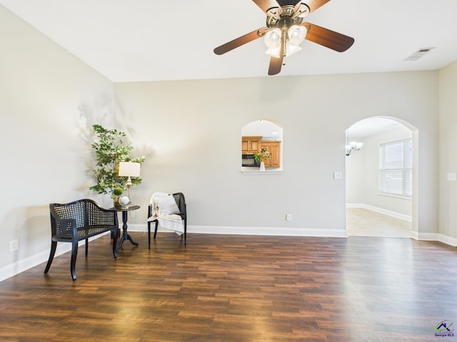 sitting room featuring visible vents, baseboards, arched walkways, and wood finished floors